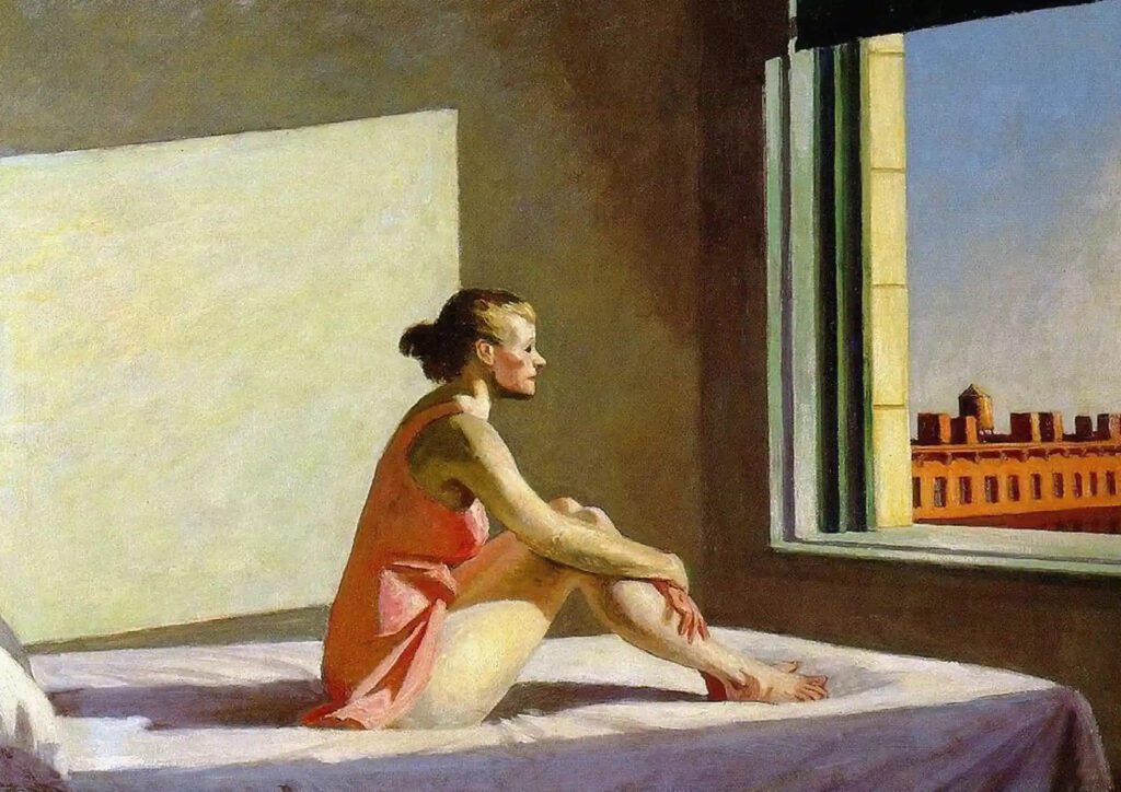 A young woman sitting on a mattress and looking out the window