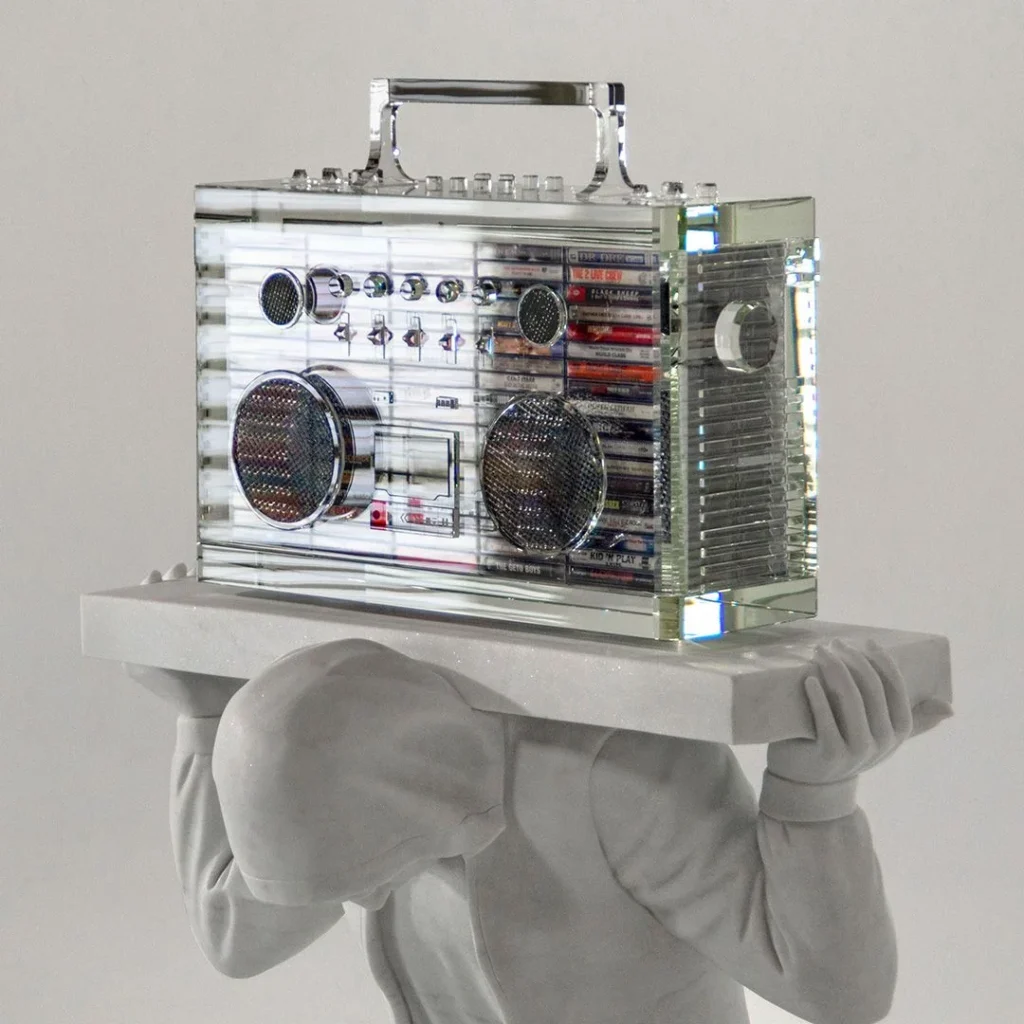 A statue of a man balancing a boombox on his head, showcasing a playful and dynamic pose.