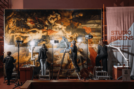 Conservators restoring a large Baroque painting in a museum studio.
